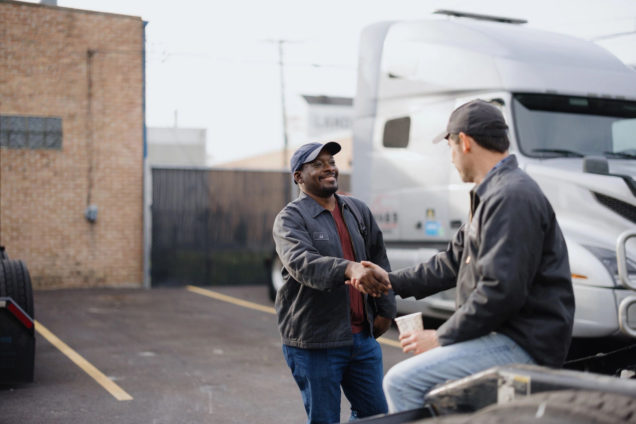 Two professionals shaking hands near trucks
